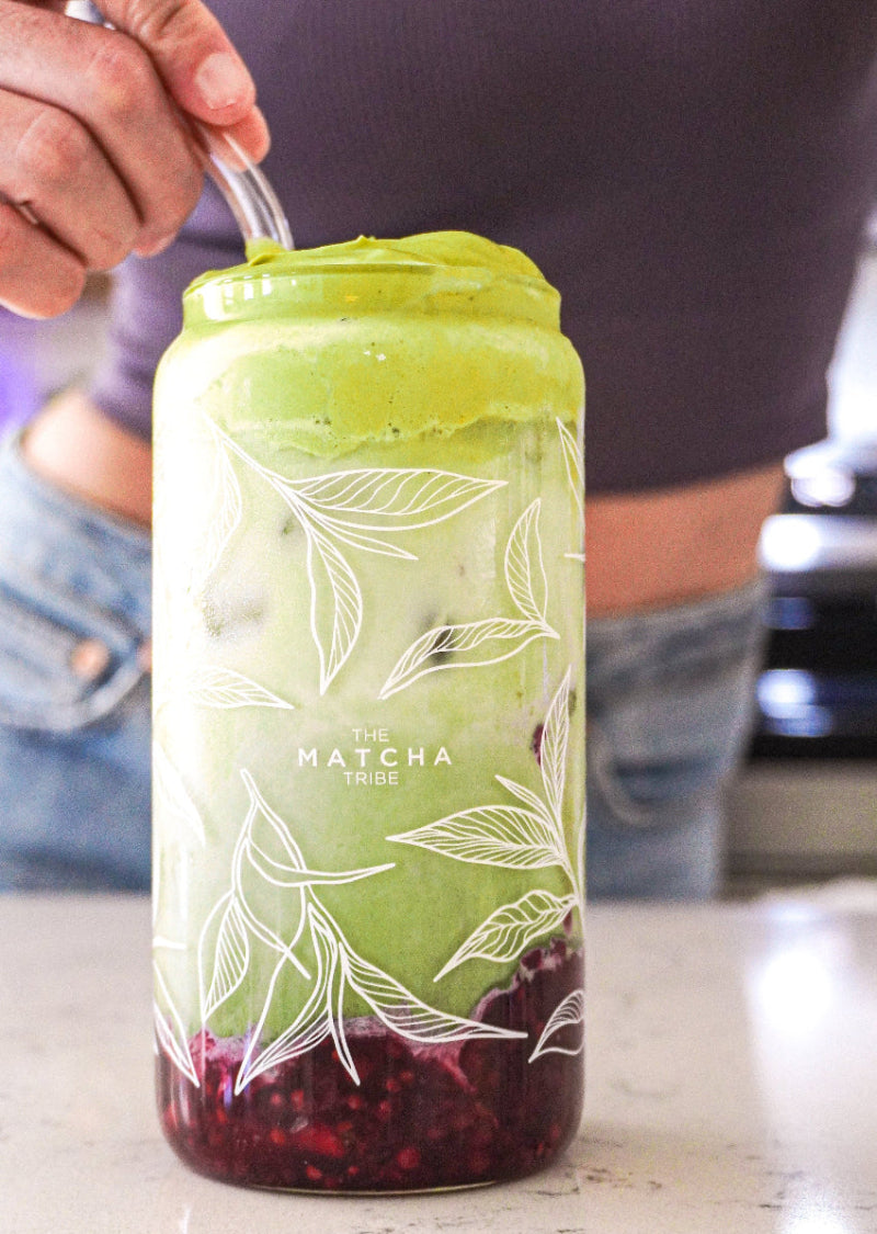 Green matcha tumbler with wooden lid and straw on a wooden surface with matching packaging.