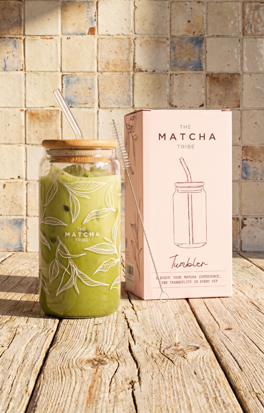 Green matcha tumbler with wooden lid and straw on a wooden surface with matching packaging.
