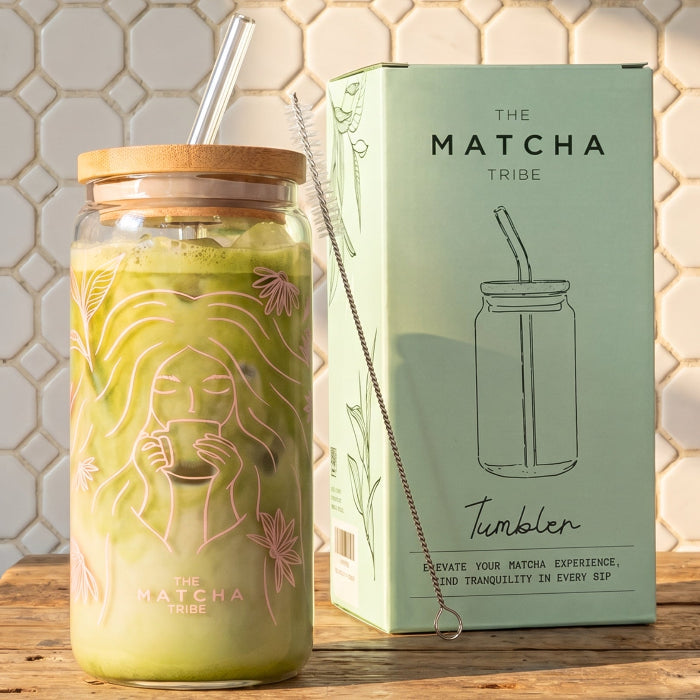 Matcha-themed tumbler with wooden lid and straw, next to a branded box on a tiled wall background.