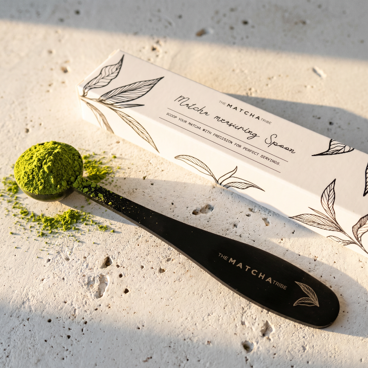 Matcha measuring spoon with a scoop of matcha powder on a textured surface