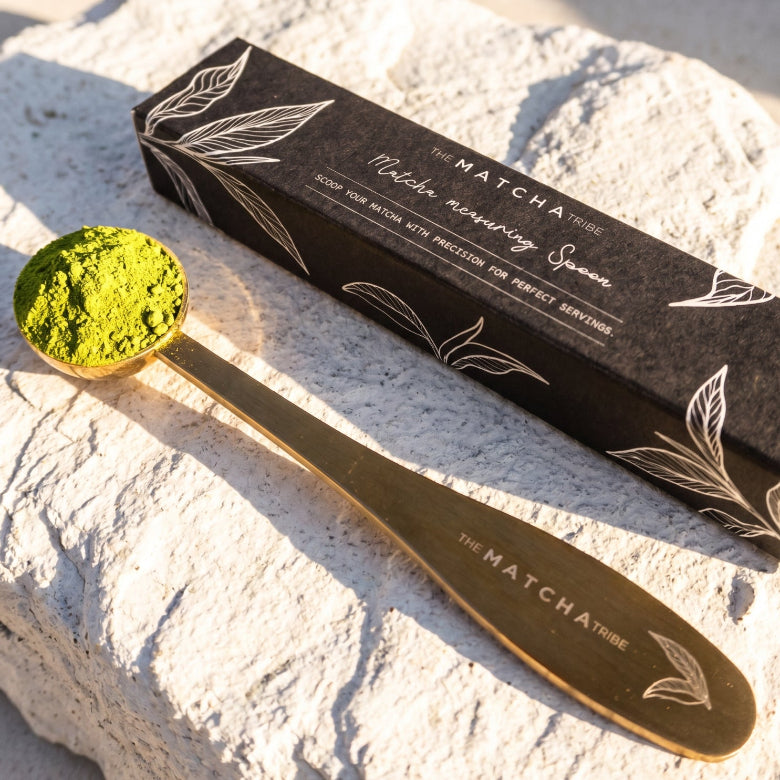 Matcha measuring spoon with matcha powder and packaging on a stone surface