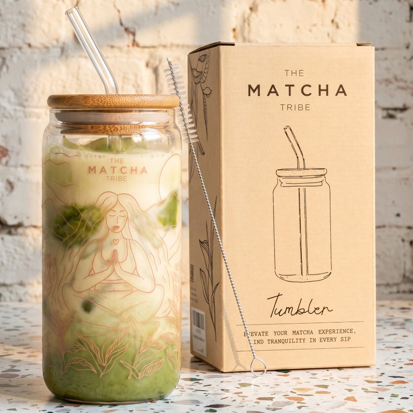 Matcha tumbler with straw and packaging labeled 'The Matcha Tribe' on a textured surface.