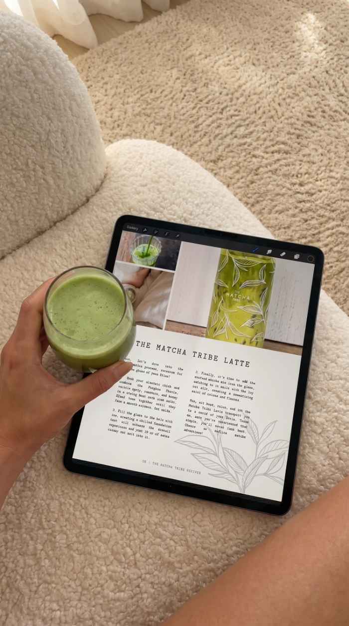 Person holding a green smoothi with a tablet displaying the matcha tribe e-book recipe